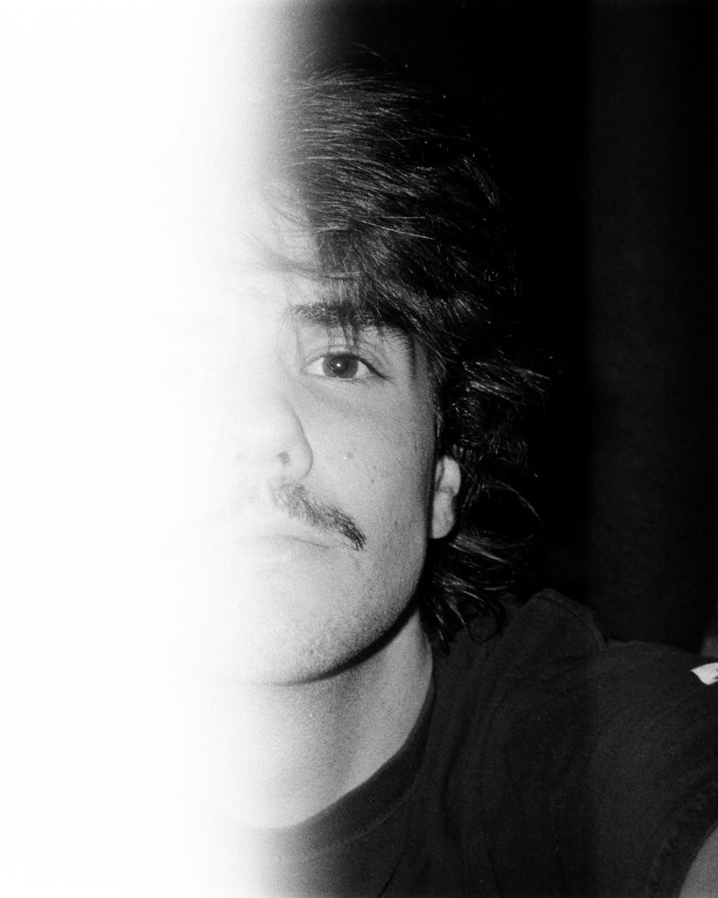 Black-and-white film self-portrait of Azariah with a light leak