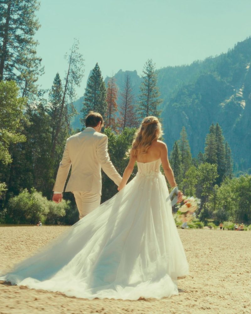 Bride and groom walking hand in hand across Cathedral Beach in Yosemite Valley