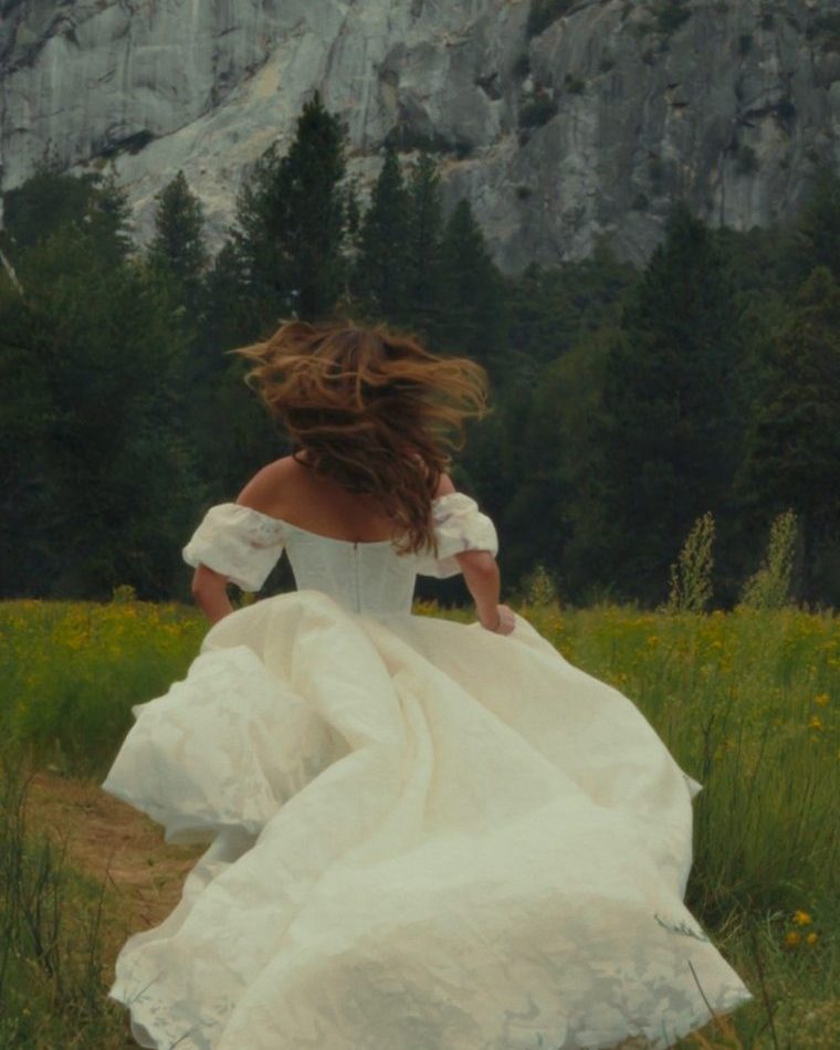 Bride running through a Yosemite Valley meadow below granite cliffs