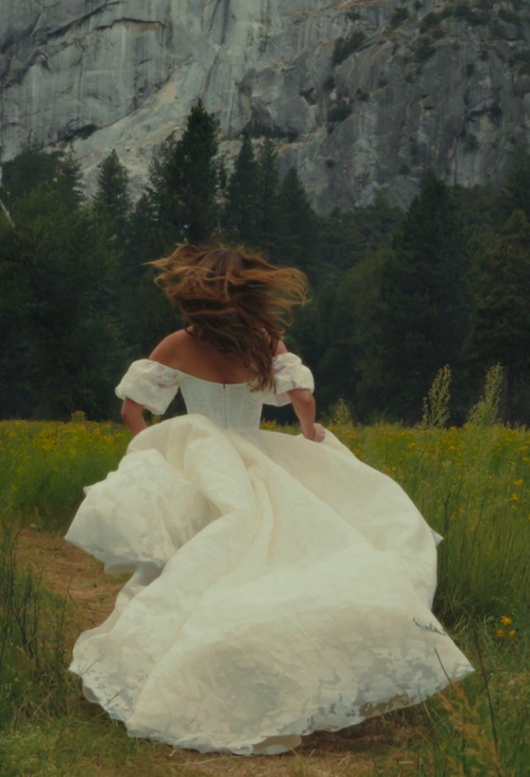 Bride running through a Yosemite meadow below granite cliffs